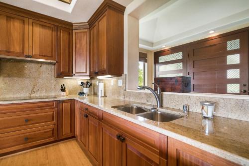 Una cocina con gabinetes de madera y un fregadero. en Tropical Villa wPrivate Pool Golf Course Views, en Waikoloa