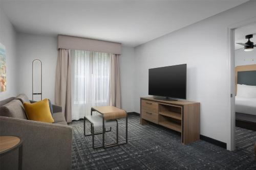 a hotel room with a television and a couch at Homewood Suites by Hilton Birmingham South Inverness in Hoover