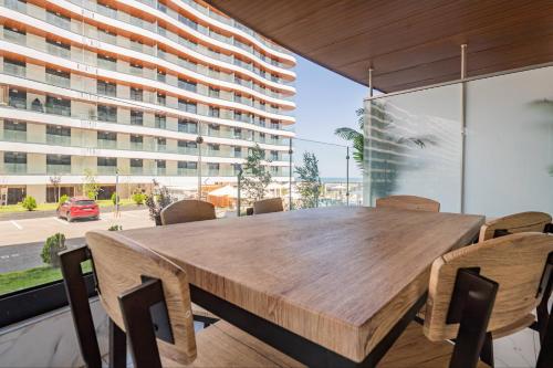 a dining room table with chairs and a large window at De Silva Apartament1 in Mamaia
