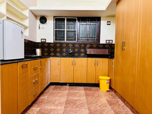 a kitchen with wooden cabinets and a window at Divine Homestay by EDAC in Chidambaram