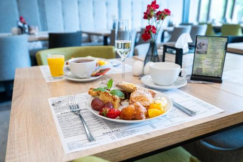 a table with a plate of food and a glass of wine at Czarny Kamień Resort & SPA in Szklarska Poręba