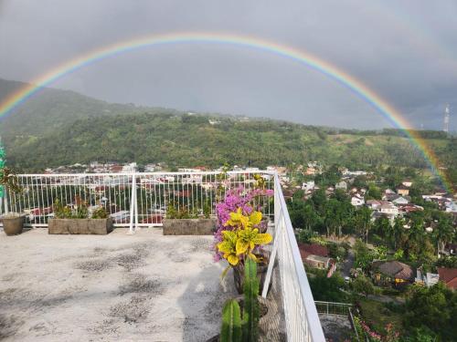 a rainbow over a balcony with flowers and a city at Arirang Sea View Homestay in Senggigi 