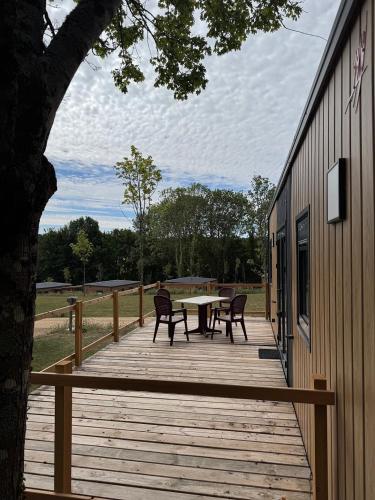 a wooden deck with a table and chairs on it at Camping Du Perche Bellemois in Bellême