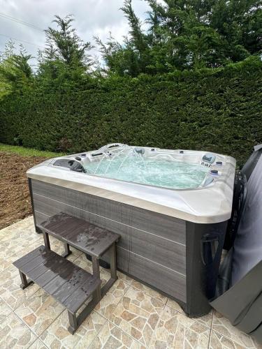 a hot tub with a bench in front of a bush at La Maison de Cristina Michael in Blois