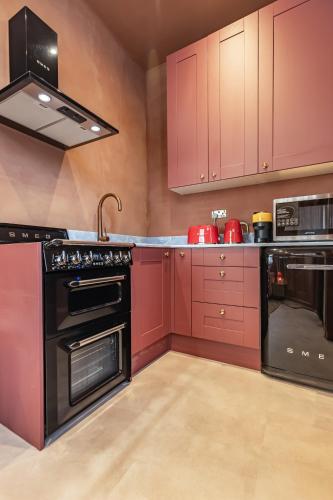 a kitchen with red cabinets and black appliances at Maison Rokxy - Luxury Apartments in London