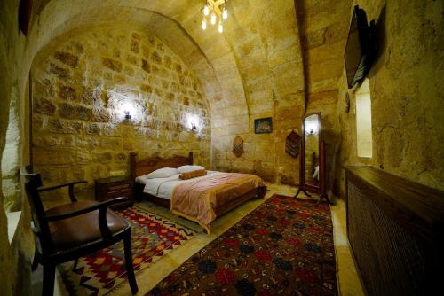 a bedroom with a bed and a chair in a room at Ürgüp Inn Cave Hotel in Urgup