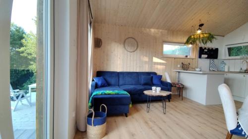 a living room with a blue couch and a table at KOCIEWSKA DACZA - domek o podwyższonym standardzie, POMORSKIE, RZEKA, LASY, ŁĄKI in Pogódki