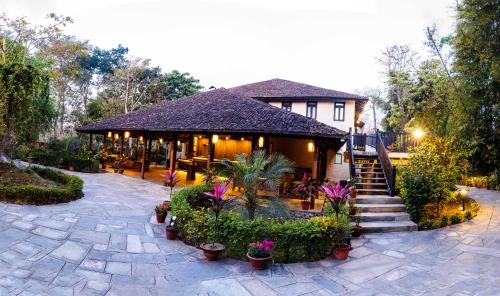 a house with a porch with plants and flowers at Banbas Resort, Chitwan in Chitwan