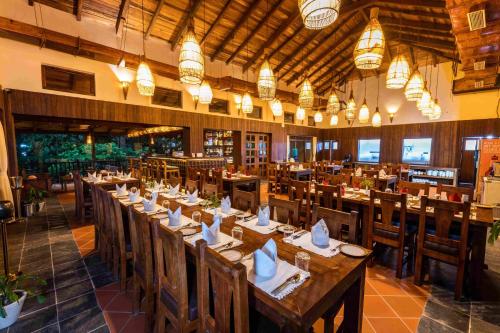 a restaurant with wooden tables and chairs and lights at Banbas Resort, Chitwan in Chitwan