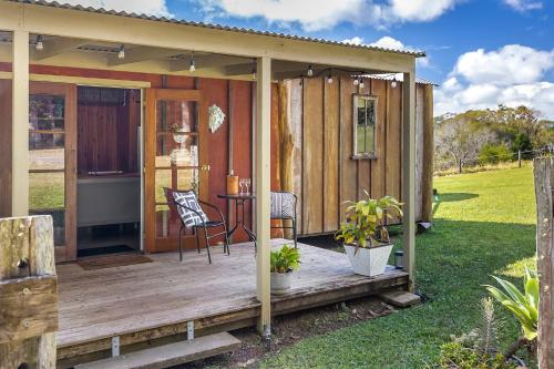 a small wooden cabin with a table on a deck at Country Cottage Sunshine Coast in Montville