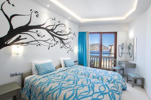 a bedroom with a bed with a tree mural on the wall at Oceanis Hotel in Karpathos Town