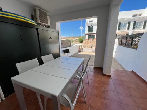 a white table and chairs in a room with a balcony at ATALAIA 11 by SOM Menorca in Fornells