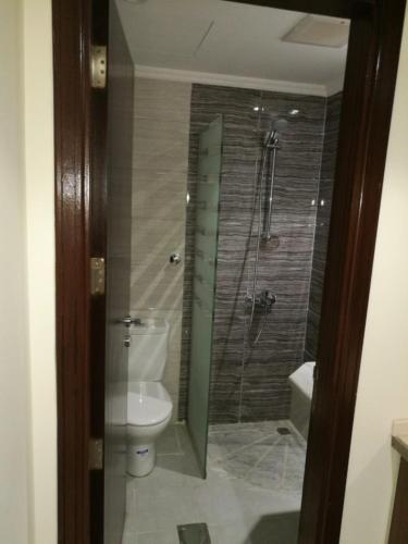 a bathroom with a toilet and a glass shower at فندق شعاع النزهة in Az Zāhir