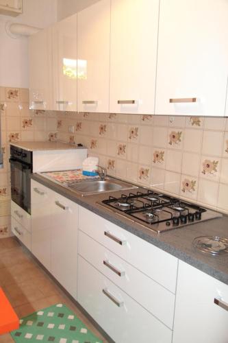 Una cocina con gabinetes blancos y un horno de estufa. en Case con bel terrazzo coperto a 2 passi dal mare, en Tortoreto Lido