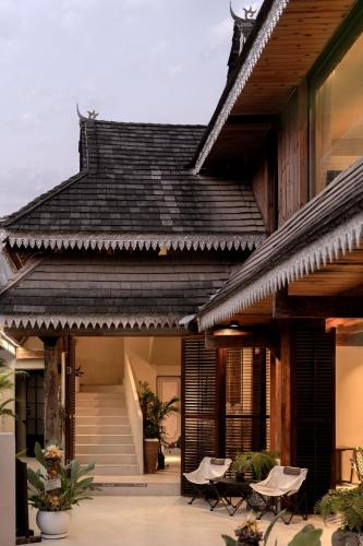 a house with a black roof with chairs and tables at M ORIGINAL VILLA in Jinghong