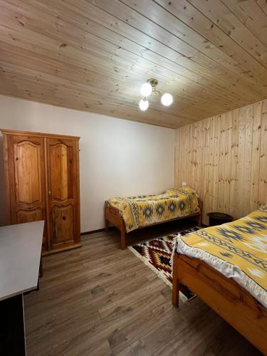 a bedroom with two beds and wooden walls at Ethno Guest House Caravan Tamchy in Tamchy