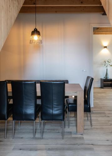 a dining room with a wooden table and black chairs at Newly Built Nature Villa, Wifi And Clean in Ledeacker
