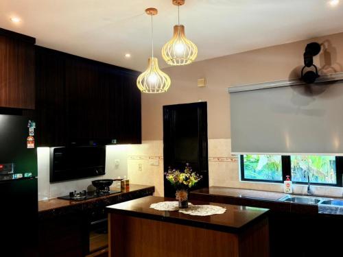 a kitchen with a center island with a vase of flowers at Sunway Lakeside Bungalow in Ipoh in Ipoh