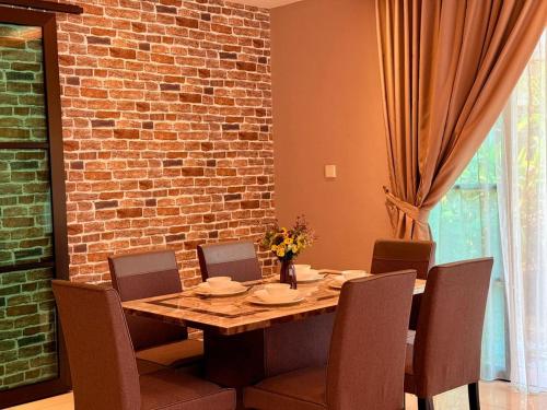 a dining room table with chairs and a brick wall at Sunway Lakeside Bungalow in Ipoh in Ipoh