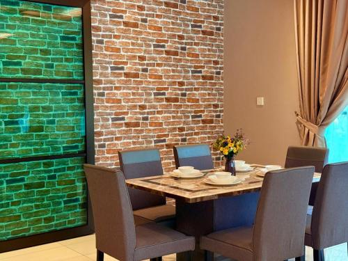 a dining room table with chairs and a brick wall at Sunway Lakeside Bungalow in Ipoh in Ipoh