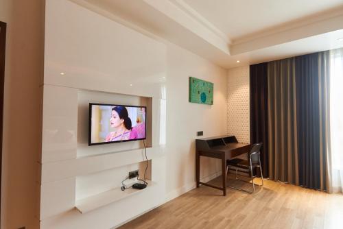 a hotel room with a television on a wall at Tania President Inn in Shirdi