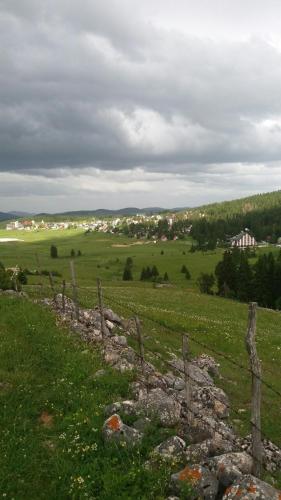 a fence in the middle of a green field at Rooms Apartment Durmitor in Žabljak