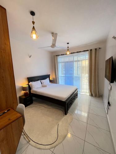 a bedroom with a bed and a large window at Tulivu Comfortable Studio Apartment in Bamburi Mombasa in Mombasa