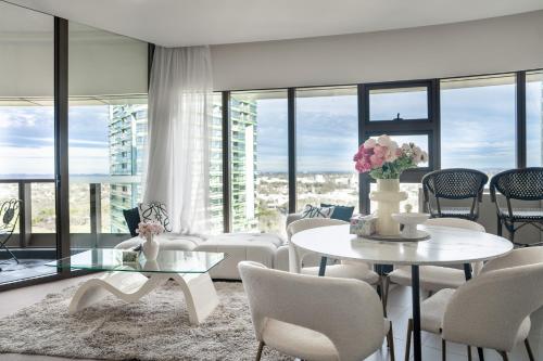 a living room with tables and chairs and windows at Skyline Serenity at Olympic Park in Sydney