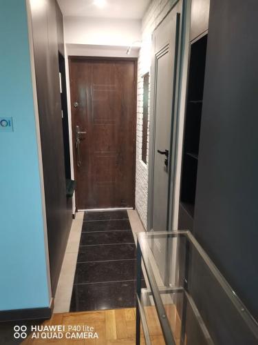 a hallway with a brown door and a staircase at Niesamowita nowoczensa kawalerka in Otwock