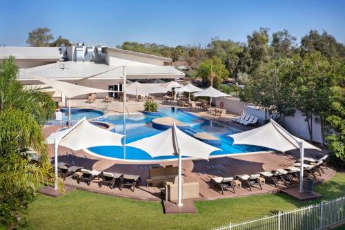 an overhead view of a resort pool with tables and umbrellas at Crowne Plaza Alice Springs Lasseters by IHG in Alice Springs