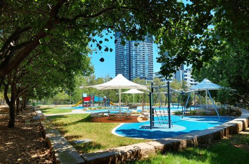 a pool with a playground with tables and umbrellas at Skyline Serenity at Olympic Park in Sydney
