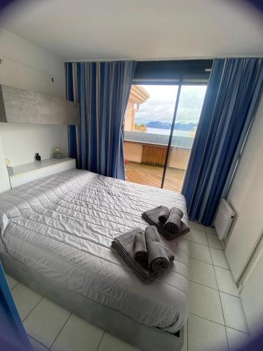 - une chambre avec un lit, des serviettes et une grande fenêtre dans l'établissement La Perla del Mare, à Cannes