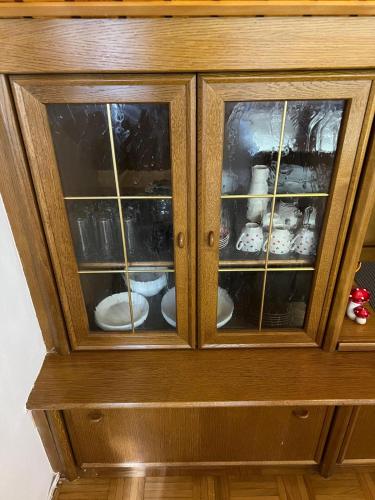 a wooden cabinet with glass doors with dishes in it at Vienna Touch Apartments Number 1 in Traiskirchen