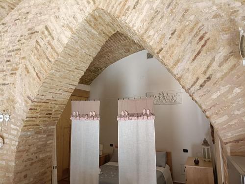a room with two white curtains and a brick wall at Il nido del Poeta in Recanati