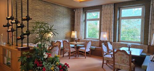 a dining room with a table and chairs and windows at Hotel Alpina in Bad Reichenhall