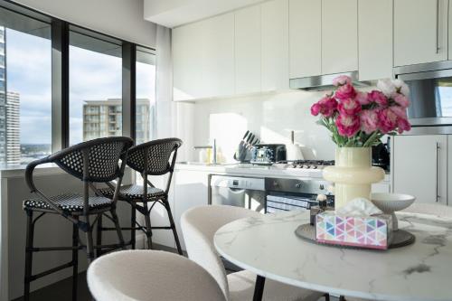 a kitchen with a table with a vase of flowers on it at Skyline Serenity at Olympic Park in Sydney