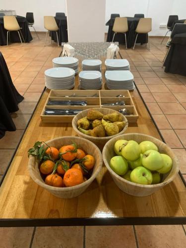 three bowls of fruit on a table with plates at Doña Lola in Castellón de la Plana