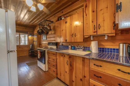 a kitchen with wooden cabinets and a white refrigerator at True Big Bear Lake Cabin with jacuzzi, Netflix in Big Bear Lake