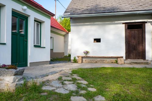 a white house with a green door and a bench at chalupa Pelechy in Kowářow