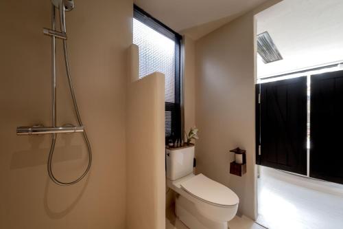 a bathroom with a white toilet and a shower at M ORIGINAL VILLA in Jinghong