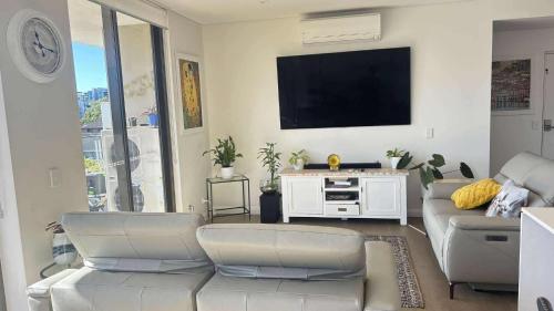 a living room with a couch and a flat screen tv at beach pad in Wollongong