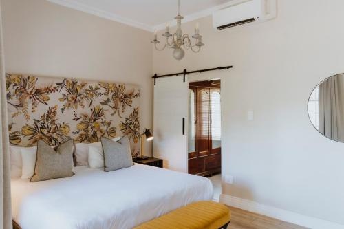 a bedroom with a white bed and a chandelier at Laborie Estate in Paarl