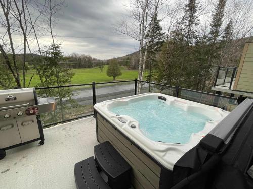 eine Whirlpool-Badewanne auf dem Balkon mit Aussicht in der Unterkunft Ski Condo & Spa - L'Elegance Des Sommets in Adstock