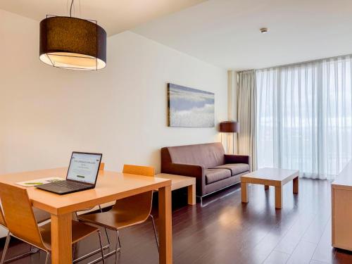 a living room with a table with a laptop on it at Hotel Jardines de Uleta Suites in Vitoria-Gasteiz