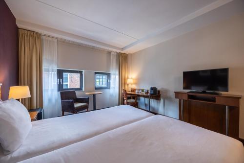 a hotel room with a bed and a flat screen tv at Amrâth Grand Hotel Frans Hals in Haarlem