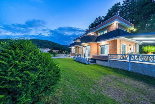 a large house with a grass yard in front of it at Peach Blossom Garden in Changdŏng-ni