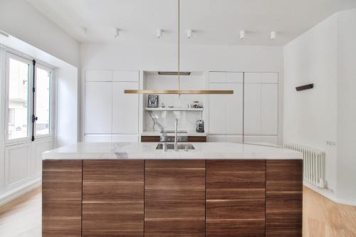 - une cuisine avec des murs blancs et un grand îlot en bois dans l'établissement Rue du Louvre - Luxury apartment, à Paris