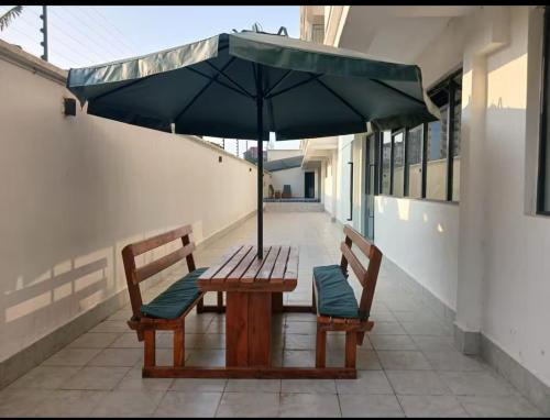 a wooden table with two benches and an umbrella at Tranquil Haven by the UN Ruaka 1BR with Pool &Gym in Ruaka