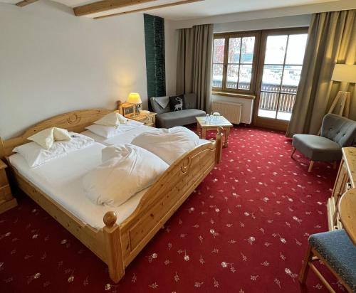 a bedroom with a large bed and a living room at Landhotel Lindenhof in Feld am See
