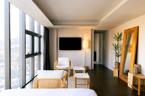 a hotel room with a bed and chairs and a tv at HOMES Red Myeongdong in Seoul